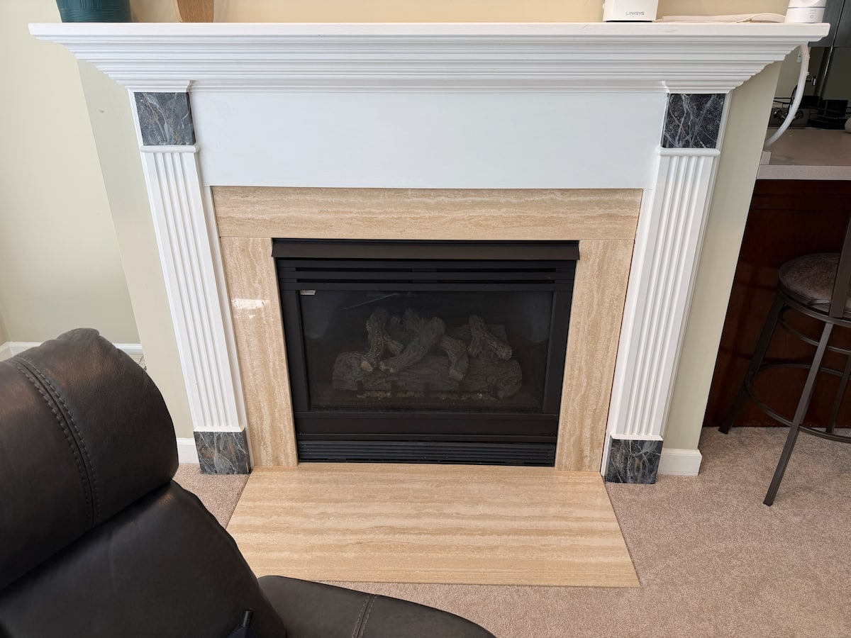 Stone-trimmed indoor gas fireplace with a white mantel in the garden-level suite
