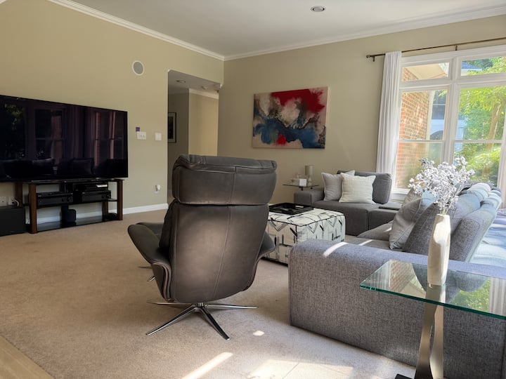 Bright lounge with sectional sofa, recliner, television, and garden windows at Butterfly Lake Retreat, Raleigh NC