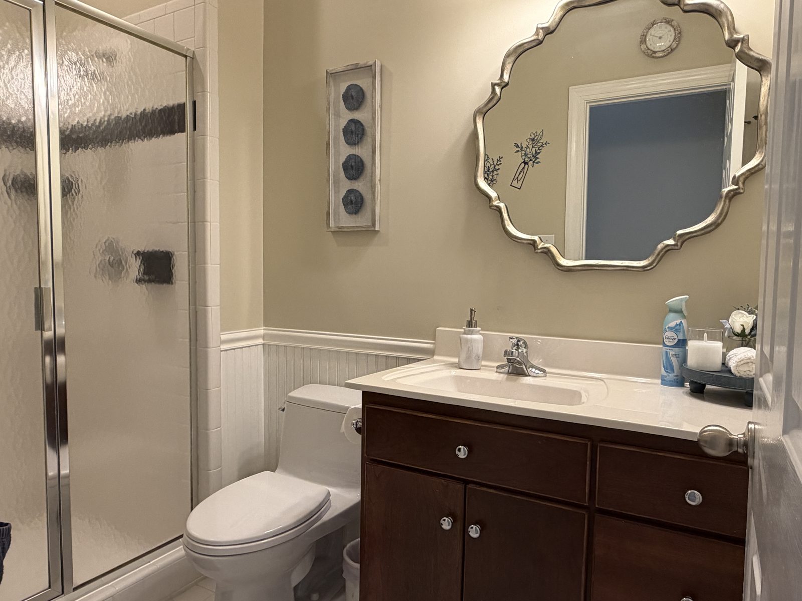 Bathroom with a glass-enclosed shower, dark wood vanity, and ornate silver-framed mirror in the garden-level suite