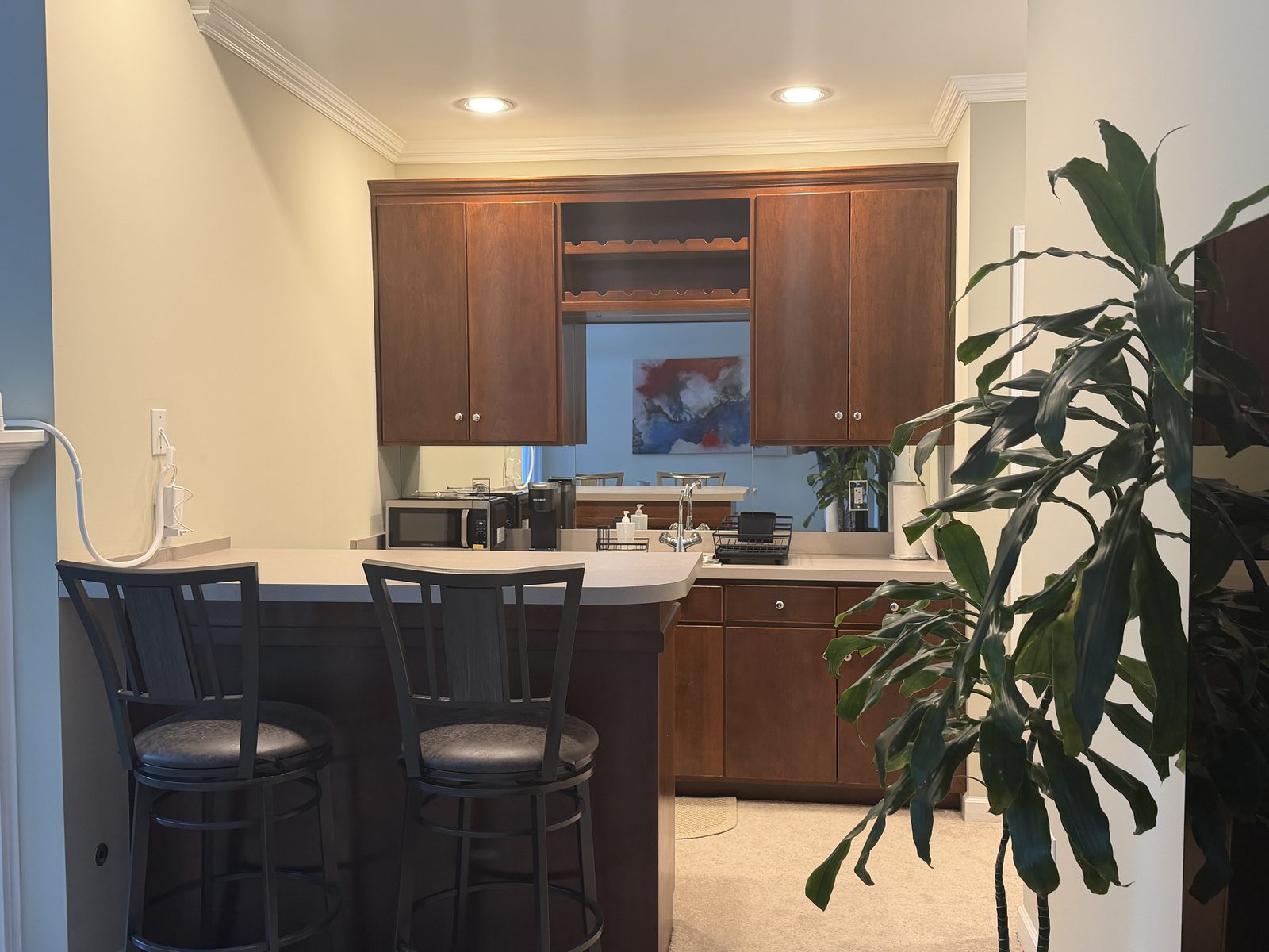 Kitchenette with wood cabinets, a breakfast bar with two stools, microwave, and Keurig coffee maker in the garden suite
