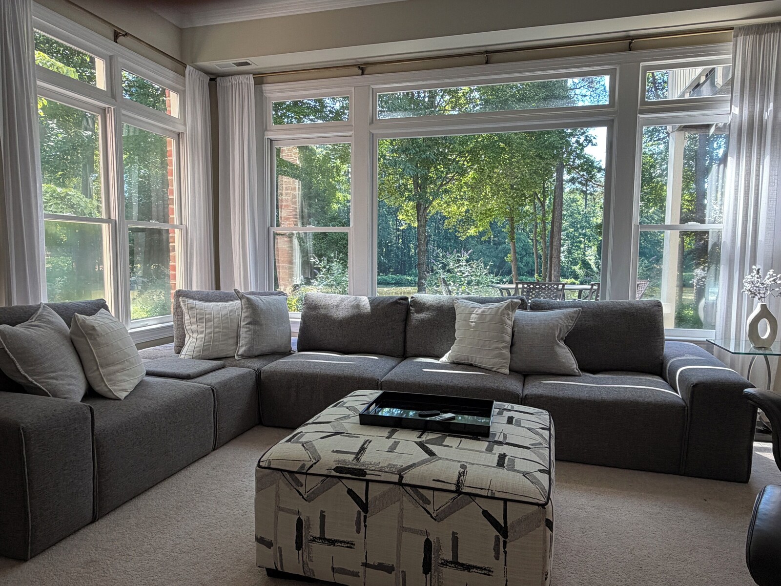 Living room with a sectional sofa and large windows looking onto the garden at Butterfly Lake Retreat, North Raleigh